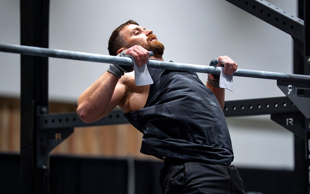 Kyle Ruth doing a pull-up in a weight vest on a rig
