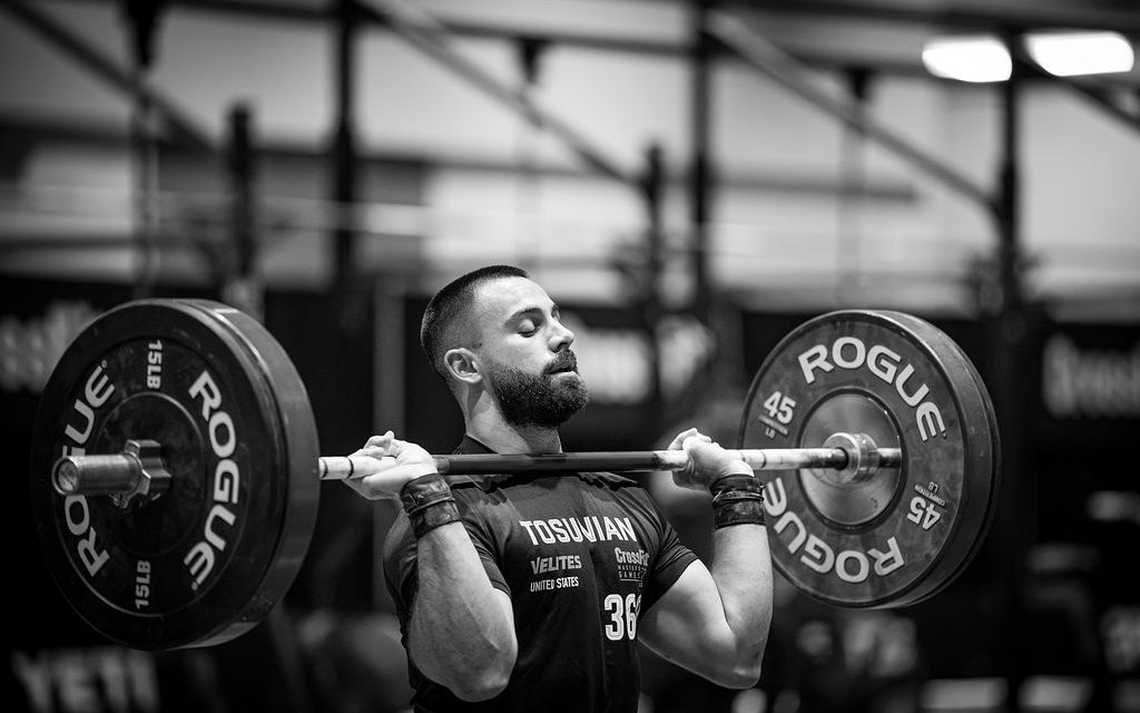 An athlete standing tall with a loaded barbell in the front rack on the competition floor