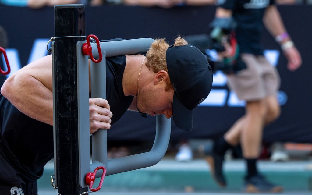 An athlete pushing a loaded sled across a competition floor