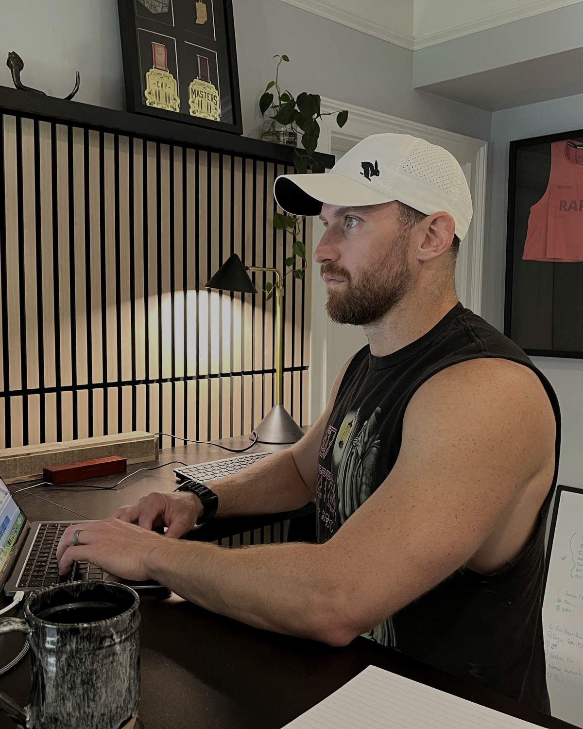Kyle Ruth writing programming at his desk, an athlete's competition jersey framed on the wall behind him